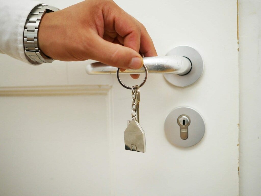 Close up shot of a hand handing a house keychain from a doorhandle